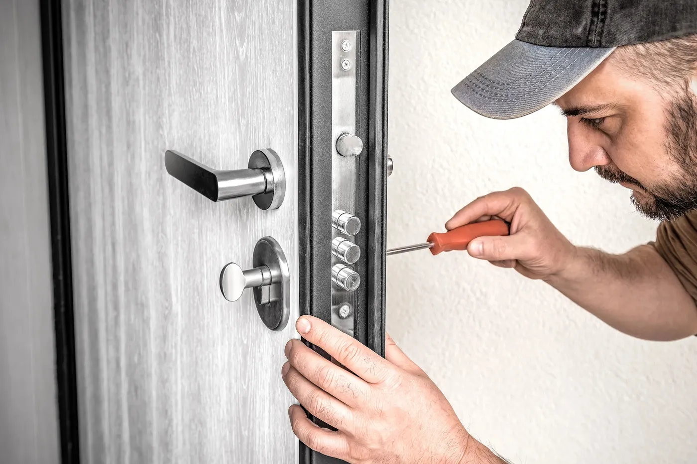 Réglage au tournevis des pênes d'une serrure multipoints sur une porte d'entrée d'un appartement du quartier Grenelle à Paris 15e